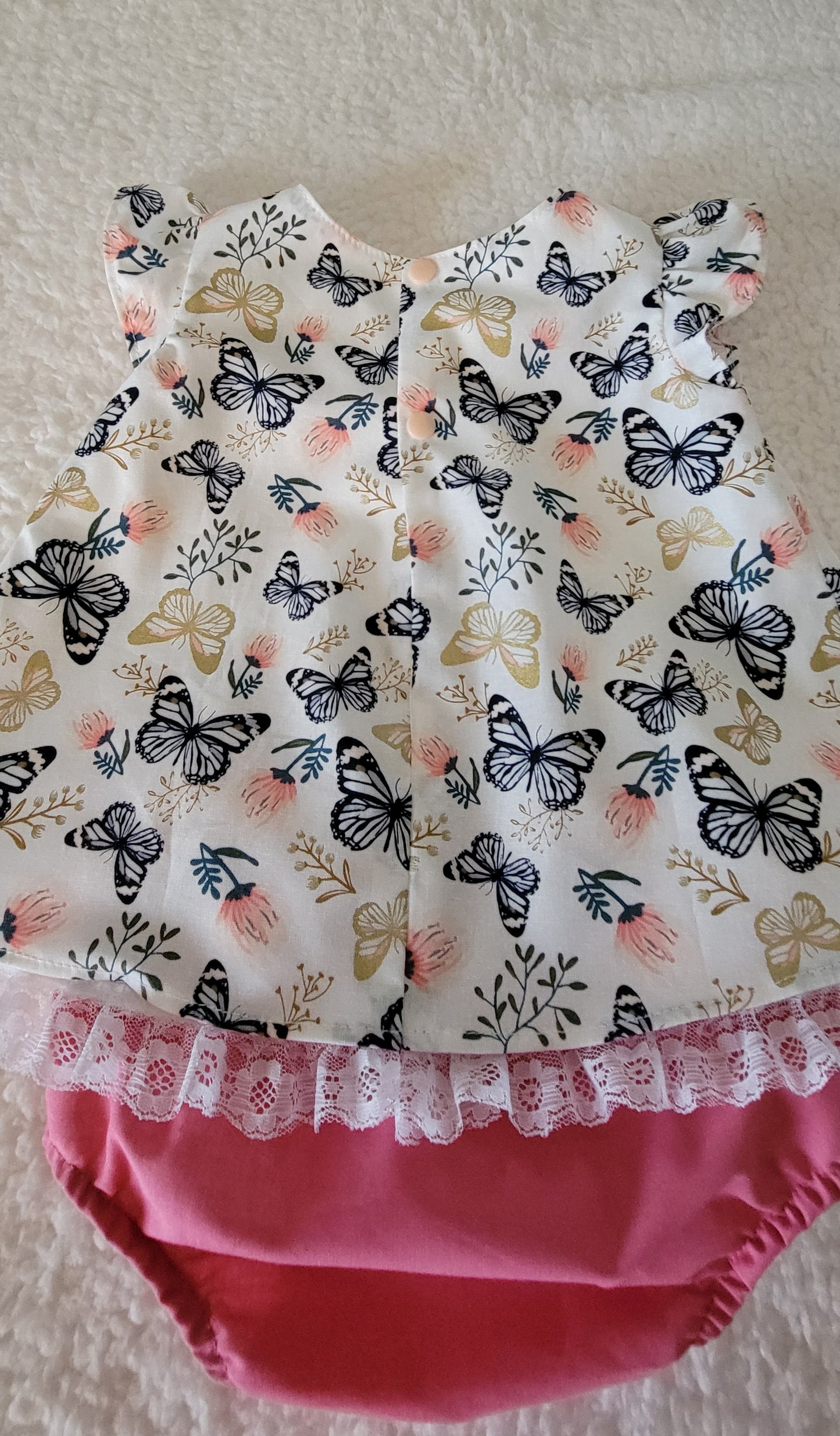 Baby outfit with butterfly pattern and pink bottom on a light background