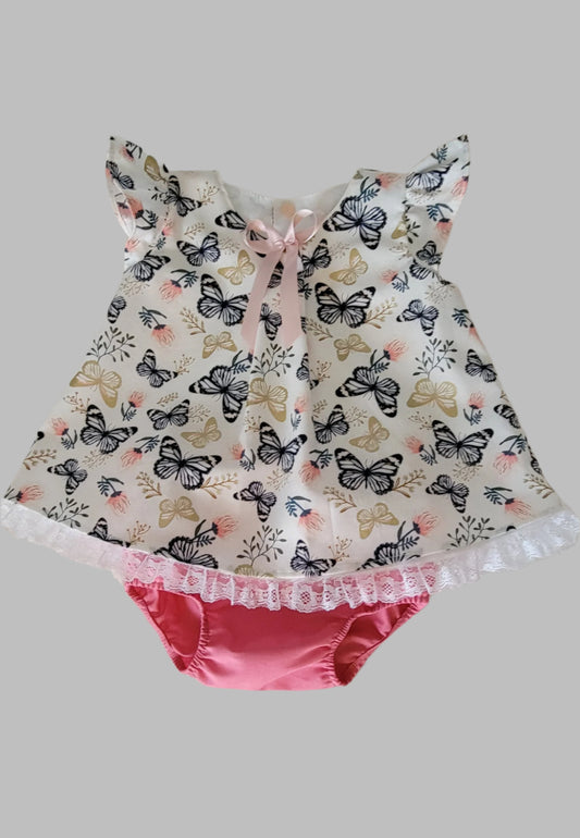 Baby outfit with butterfly pattern top and pink bloomers on a textured surface