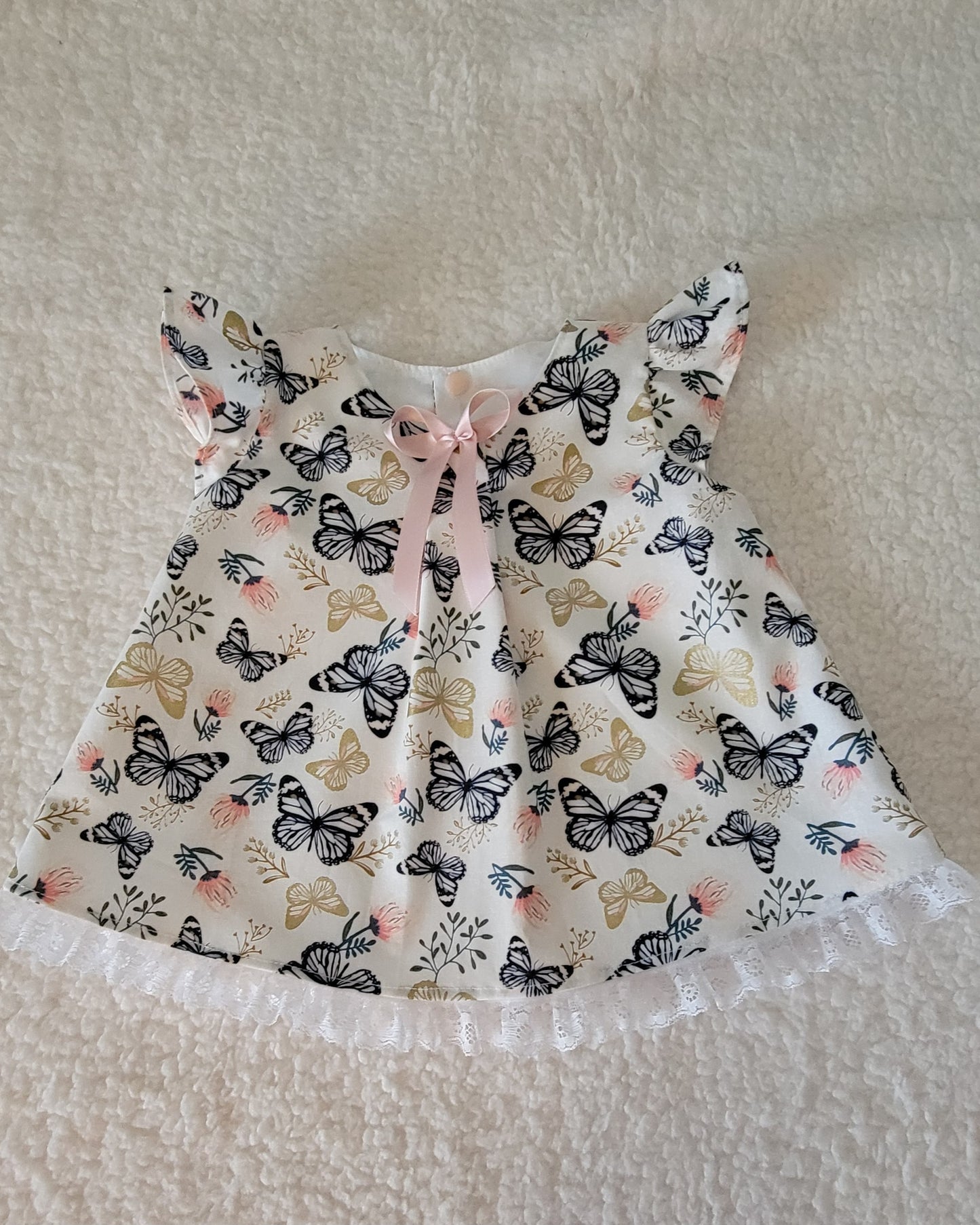 Baby dress with butterfly pattern on a textured surface