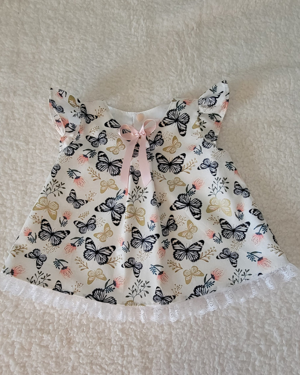 Baby dress with butterfly pattern on a textured surface
