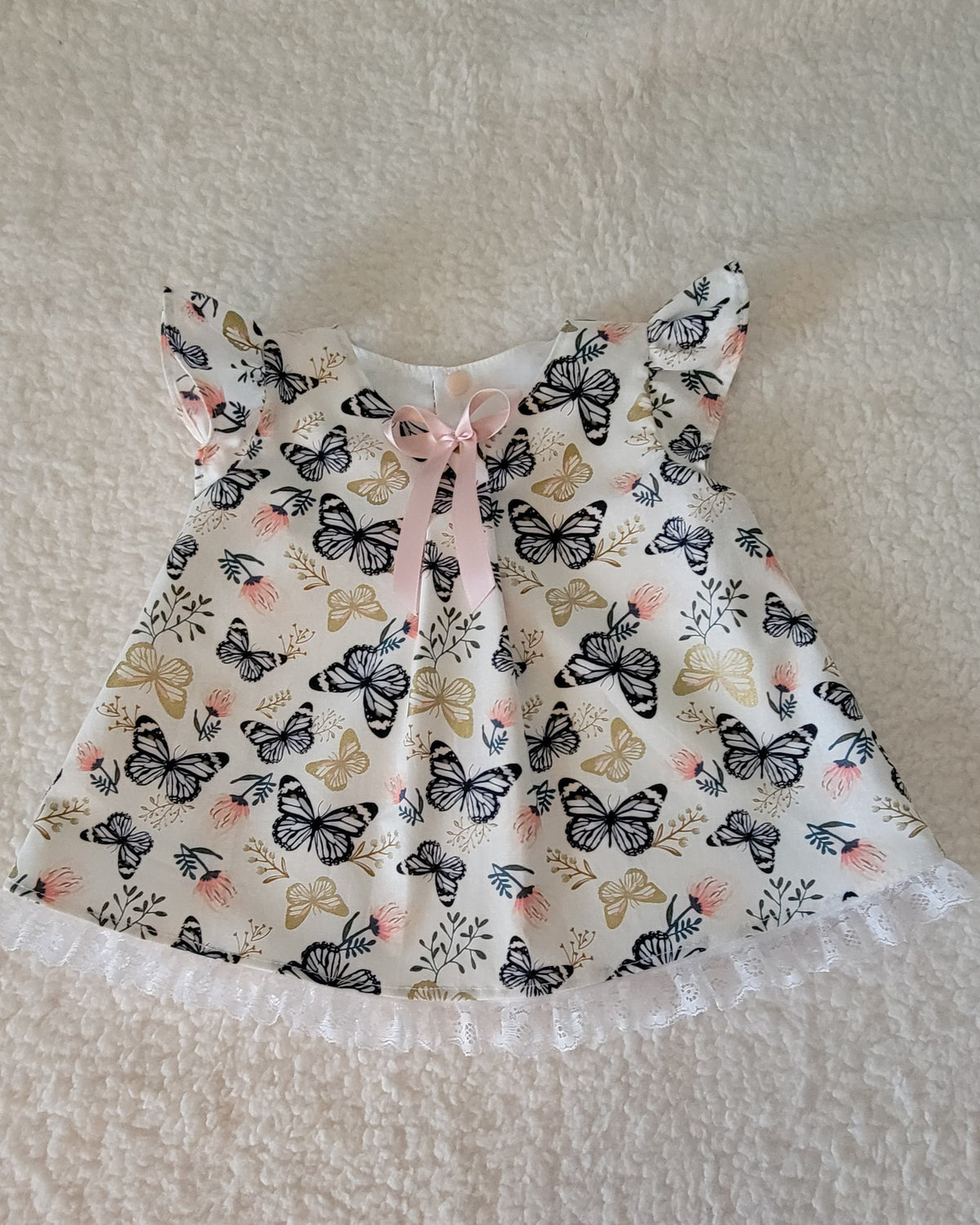 Baby dress with butterfly pattern on a textured surface